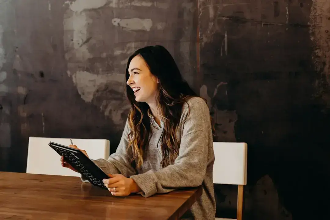 Woman smiling at table with clipboard